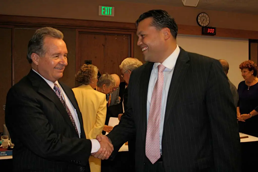 Larry Anderson, CEO of Tri-City Healthcare District, left, and Kirkpatrick Kapua Conley, CEO of Fallbrook Hospital, shake hands following approval of the JPA on June 27. The agreement ensures uniform care for patients in both healthcare districts. Photo by Promise Yee