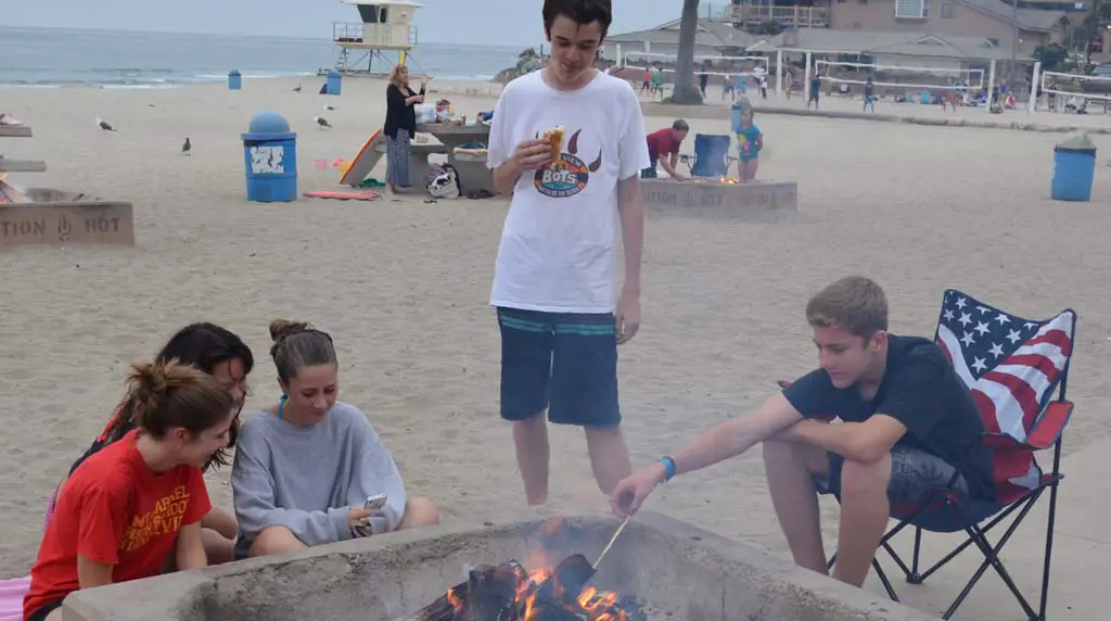 Teens sit around a fire pit at Moonlight Beach. The Encinitas City Council will give the thumbs up or down to a reservation system for three or four of the fire pits at the beach. Photo by Jared Whitlock