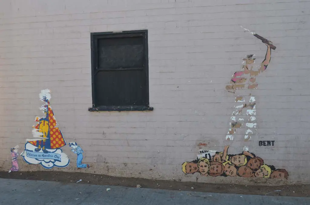 The faded remnants of street art from the anonymous street artist BERT, right, and a work signed by OZI recently appeared on a building wall in Encinitas. Photo by Tony Cagala