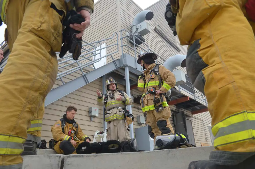 Following live fire training, Battalion Chief Bret Davidson, center, provides a rundown of what he saw during a fire behavior observation exercise. Also pictured, Firefighter Nick Chapin, far left, and Capt. Greg Rainville. Photo by Tony Cagala