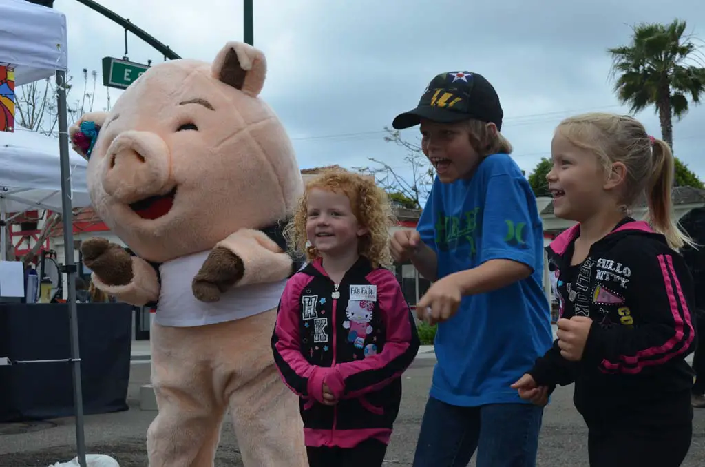 From left: Porkchop, Reese Hilliard, Brady Hilliard and Riley Hilliard do some dancing in the streets in Encinitas. Porkchop will be part of the San Diego County Fair (Del Mar Fairgrounds) Big Bite Baconfest July 5. Photo by Tony Cagala