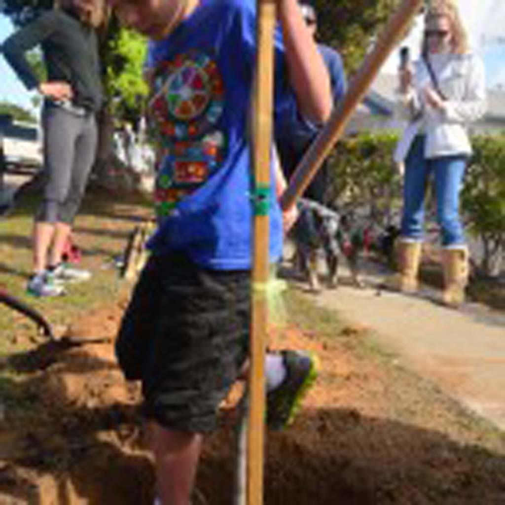Jakob Ugrob, 8, stomps down on some dirt where a tree was planted during an Arbor Day celebration. Photo by Tony Cagala