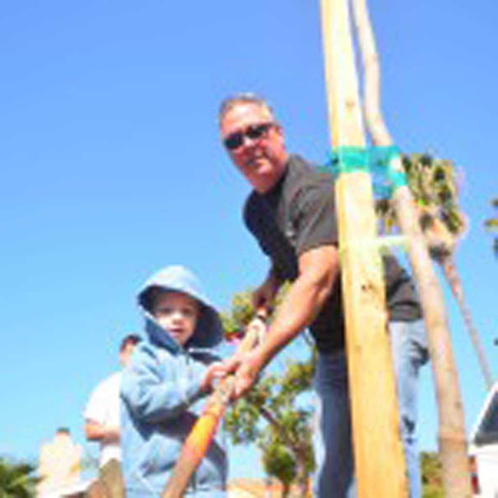 Dennis Philbin, right, with grandson Kayden Philbin work together to plant a tree. Photo by Tony Cagala
