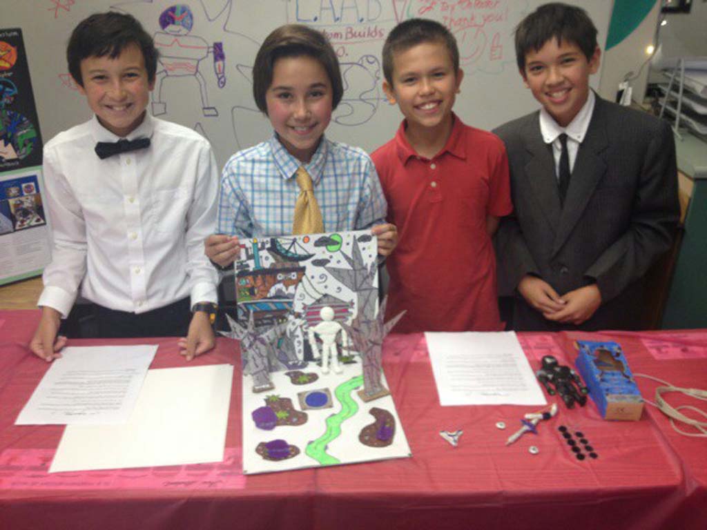 From left: Luke Kleinrath, Alexander Poroy, Daniel Gurholt and Adam Olander showcase their project during Ada Harris School’s second annual Toy Fair. The team created an action figure called “Legends of Jhiaxus.” Photo by Aaron Burgin