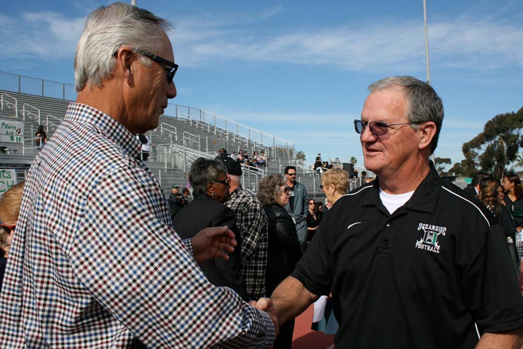 Former superintendent Larry Perondi shakes hands with Coach John Carroll before the dedication. Oceanside High School stadium was named after Carroll on Dec. 8. Photo by Promise Yee