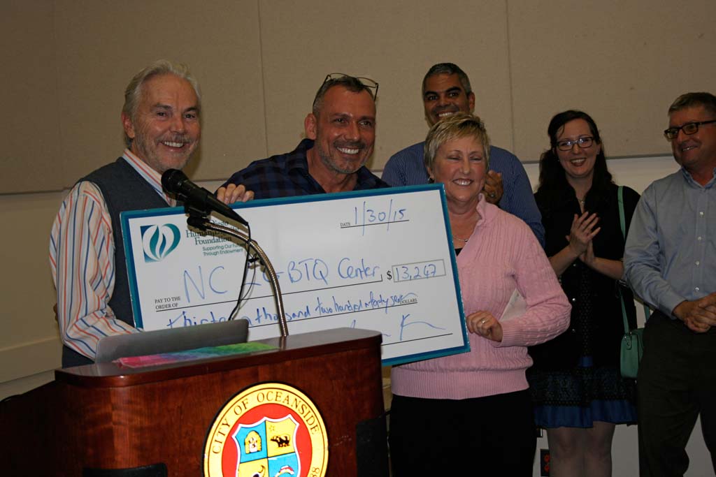 On far left San Diego Human Dignity Foundation executive director John Brown hands LGBTQ Center Executive Director Max Disposti a check to fund programs. The foundation gave the center the greatest amount in donations last year. Photo by Promise Yee