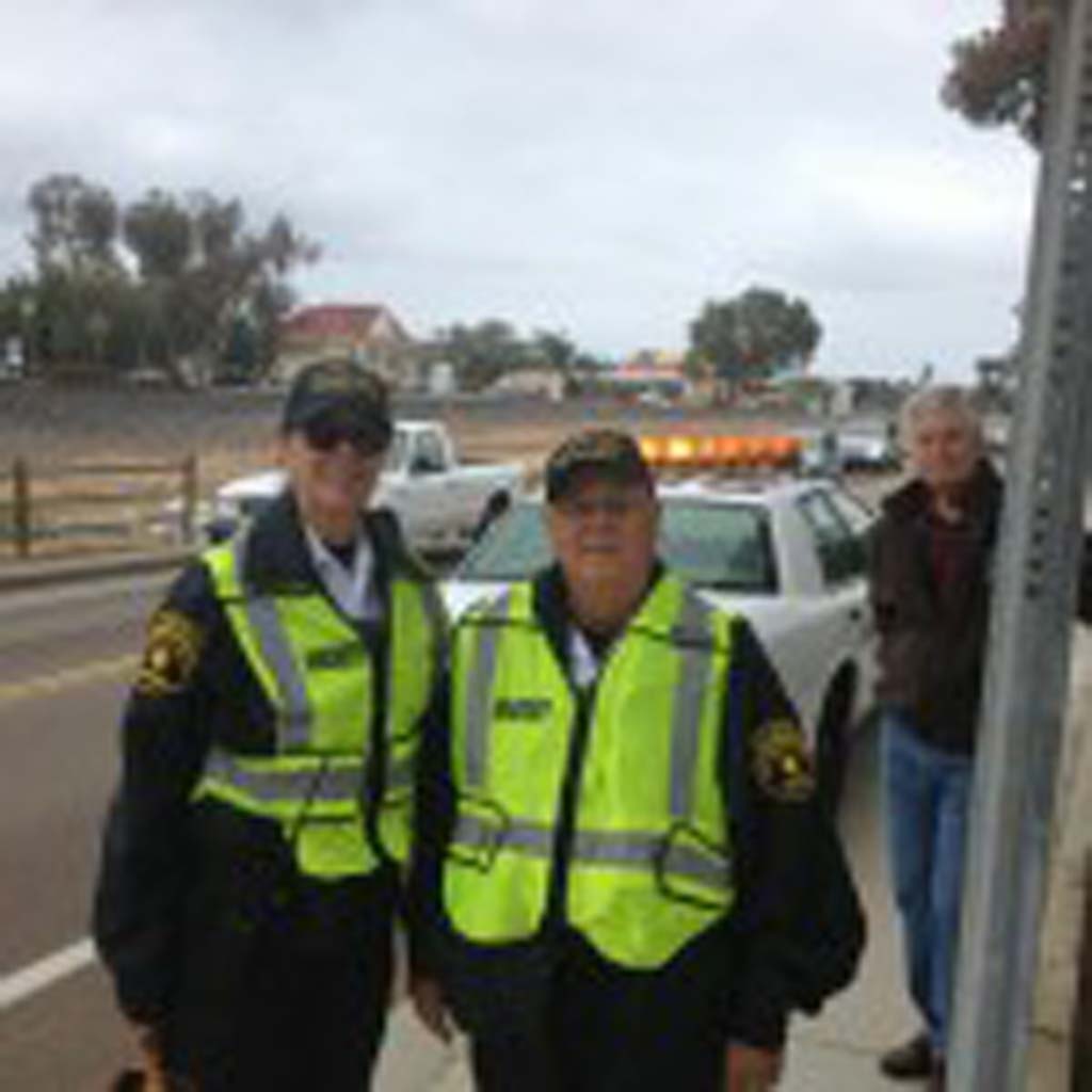 Encinitas Sheriff’s volunteers Leslie Echter, left, Jerry Jerome, center, and Larry Peetoom, keep an eye out in front of Paul Ecke Central in an effort to slow down traffic that had been endangering students and their parents at the elementary school for some time. Photo by Aaron Burgin