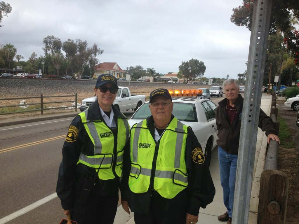 Encinitas Sheriff’s volunteers Leslie Echter, left, Jerry Jerome, center, and Larry Peetoom, keep an eye out in front of Paul Ecke Central in an effort to slow down traffic that had been endangering students and their parents at the elementary school for some time. Photo by Aaron Burgin