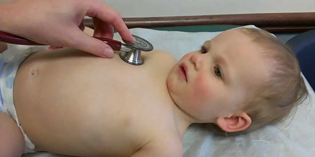 A young girl, age 15 months, undergoing a physical examination. The pediatrician is using a stethoscope on the right side of the child's chest. Photo by Ragesoss courtesy of WikiMedia
