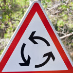Roundabout triangle traffic sign on nature background. Stock photo