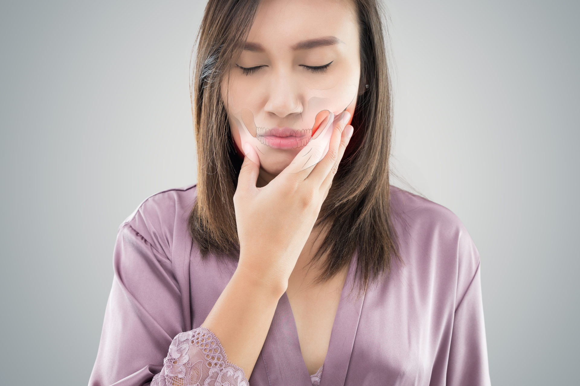Temporomandibular Joint and Muscle Disorder: TMD, Suffering from toothache. Beautiful young woman suffering from toothache while standing against grey background