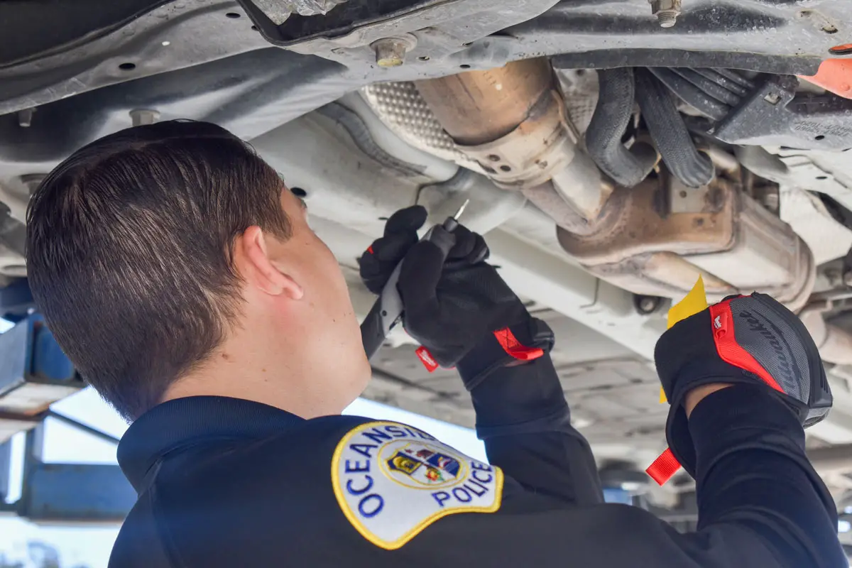 Oceanside Police Det. Mark Theriot etches a vehicle's license plate number into its catalytic converter during an anti-theft event on March 12at Len's Auto Body in Oceanside.