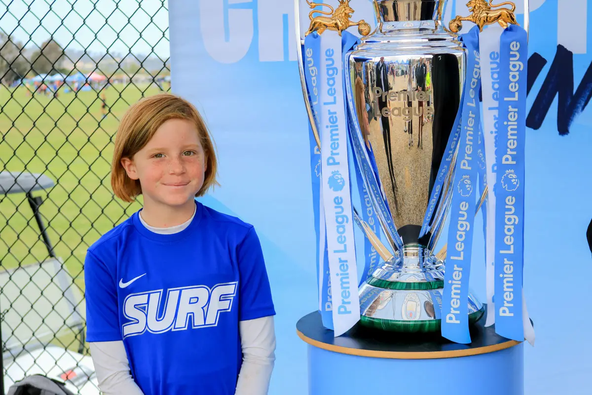 San Diego-area Surf Soccer Club player Anna Moore gets her photo taken with the English Premier League trophy during the Nexen Manchester City Cup tournament on Sunday at Surf Cup Sports Park in Del Mar. Photo by Laura Place