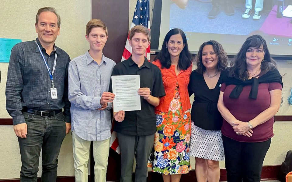 (Left to right) La Costa Canyon High School seniors Shane and Andrew Baum, center, show off their gun violence prevention resolution passed by the San Dieguito Union High School District board on Aug. 25 with trustees Michael Allman and Katrina Young, Superintendent Tina Douglas, and Trustee Mo Muir. Courtesy photo