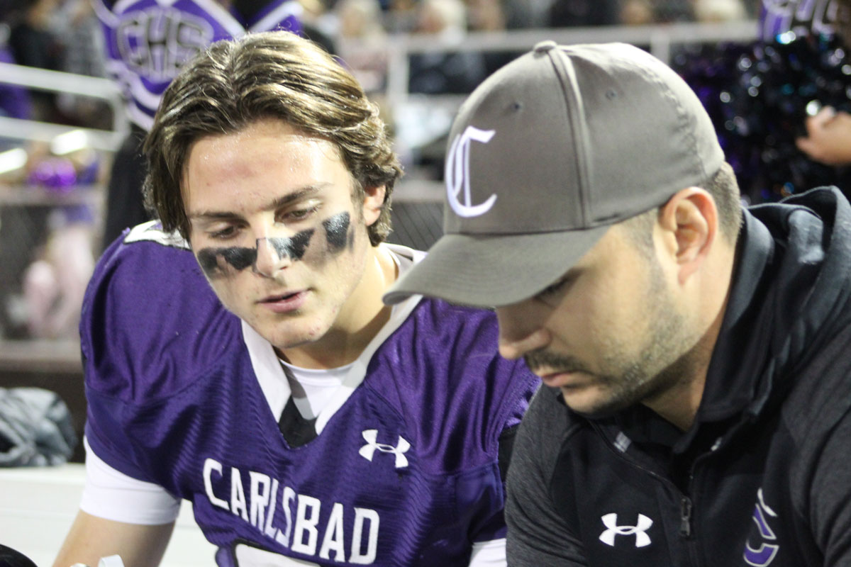 Carlsbad High School quarterback Julian Sayin, left, discusses strategy with CHS quarterback coach Christian Champan during the Lancers’ 37-0 win over Poway on Nov. 10 in Carlsbad. Photo by Steve Puterski