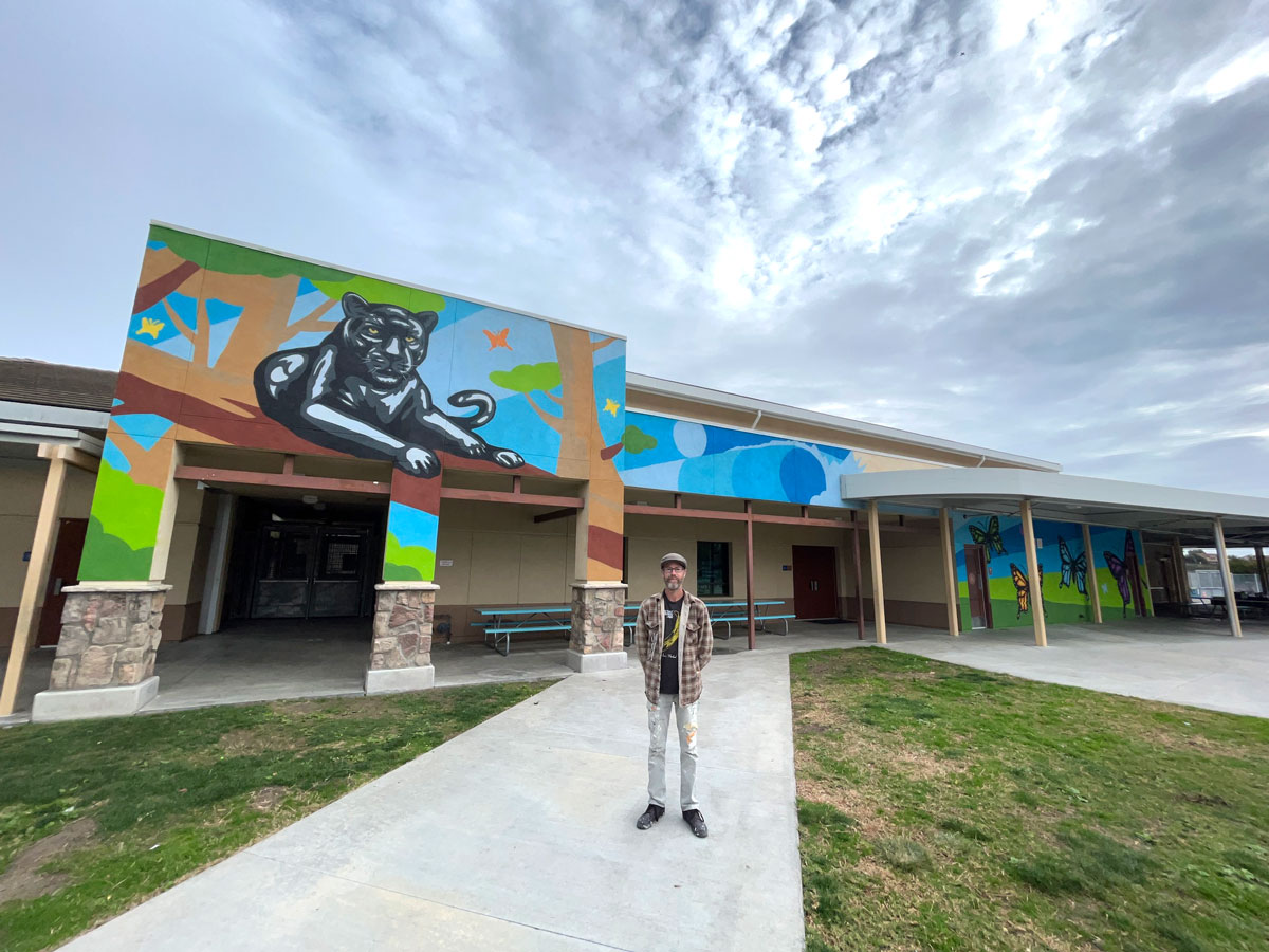 Valley Middle School teacher and local artist Bryan Snyder stands in front of a new mural he painted during Christmas break at Poinsettia Elementary School. Courtesy photo/Bryan Snyder