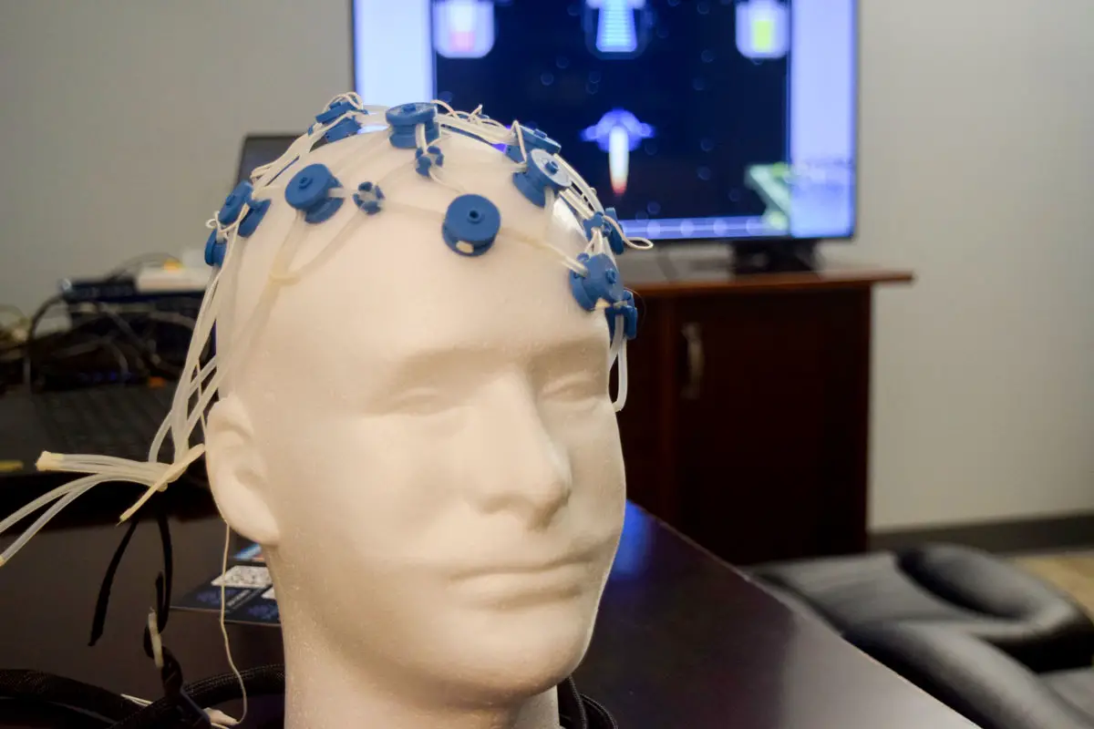 An electrode head harness model patients would use during a session with Lisa Tataryn at her clinic with a preview of one of the games to measure brain waves in the background. Photo by Kaila Mellos