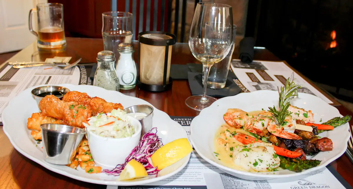 (Left to right) Green Dragon’s Beer Battered Fish ‘N Chips with garlic parmesan fries, and slaw. Seafood Mixed Grill Trio with cod, salmon, and shrimp with Old Bay aioli and vegetables. Photo by Rico Cassoni