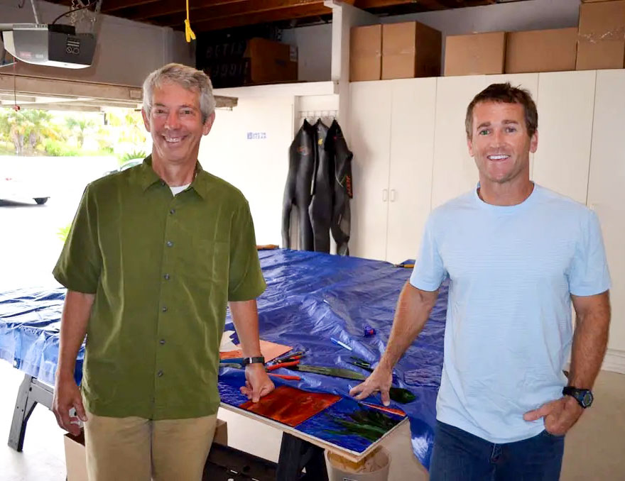 Surfing Madonna artist Mark Patterson, left, and Bob Nichols, operations director of the nonprofit Surfing Madonna Oceans Project, pose in front of a sequel to the Surfing Madonna. The tarp will be taken off this fall, revealing the new mosaic. Photo by Jared Whitlock
