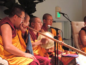 Venerable Geshe Tenzin Lekshey (far left) plays the Tibetan long trumpet during the sand mandala opening ceremony. Photo by Abigail Sourwine