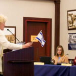 Community member Marci Strange holds an Israel flag while speaking on Oct. 26 to the San Dieguito Union High School District board. Photo by Laura Place