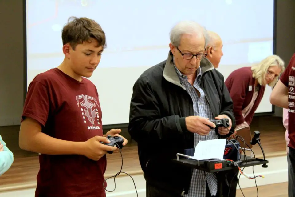Austin Fogarty, 14, a freshman on the Tri-City Christian High School Robotics Team, plays a robot game with La Costa Glen resident Larry Greenfield on Tuesday. Photo by Laura Place