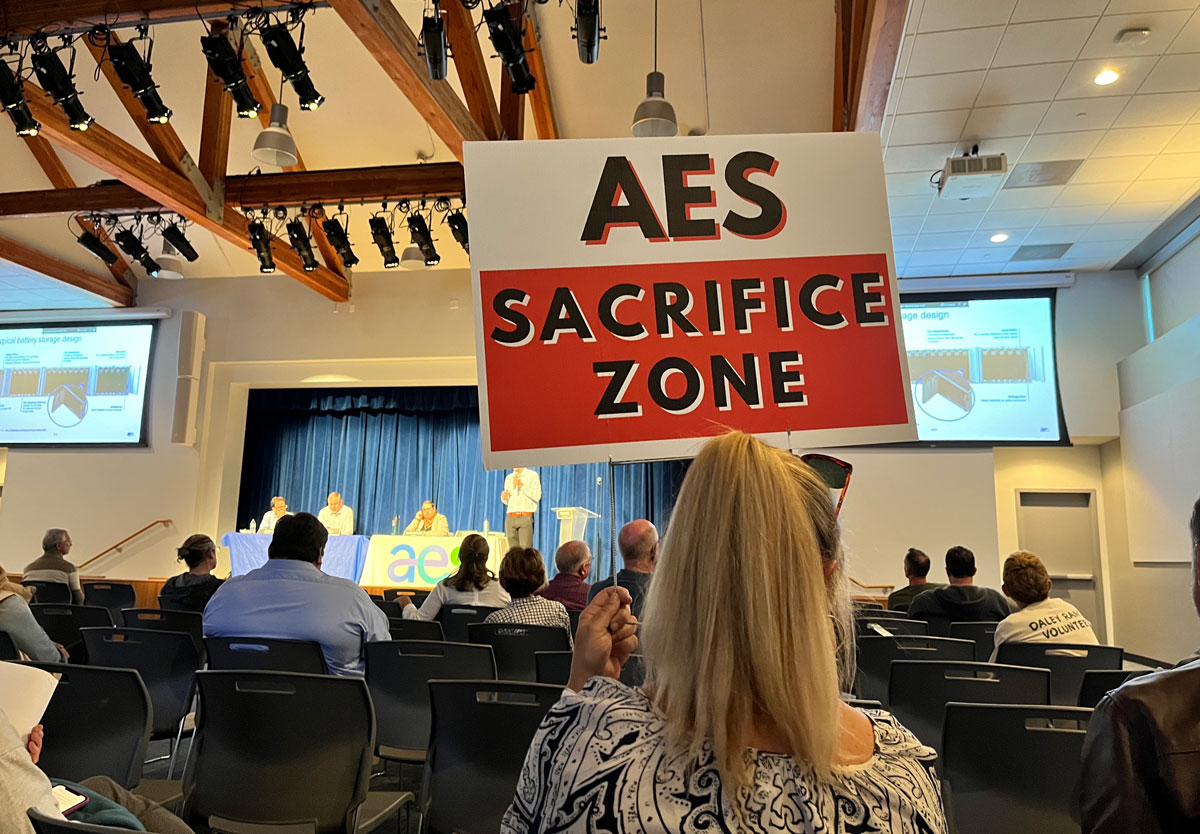 A resident holds an “AES Sacrifice Zone” sign during a March 20 workshop in San Marcos. Photo by Samantha Nelson