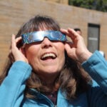 Solana Beach resident Anita Flagg takes a look at the partial solar eclipse on April 8 at the Encinitas Public Library. Photo by Jordan P. Ingram