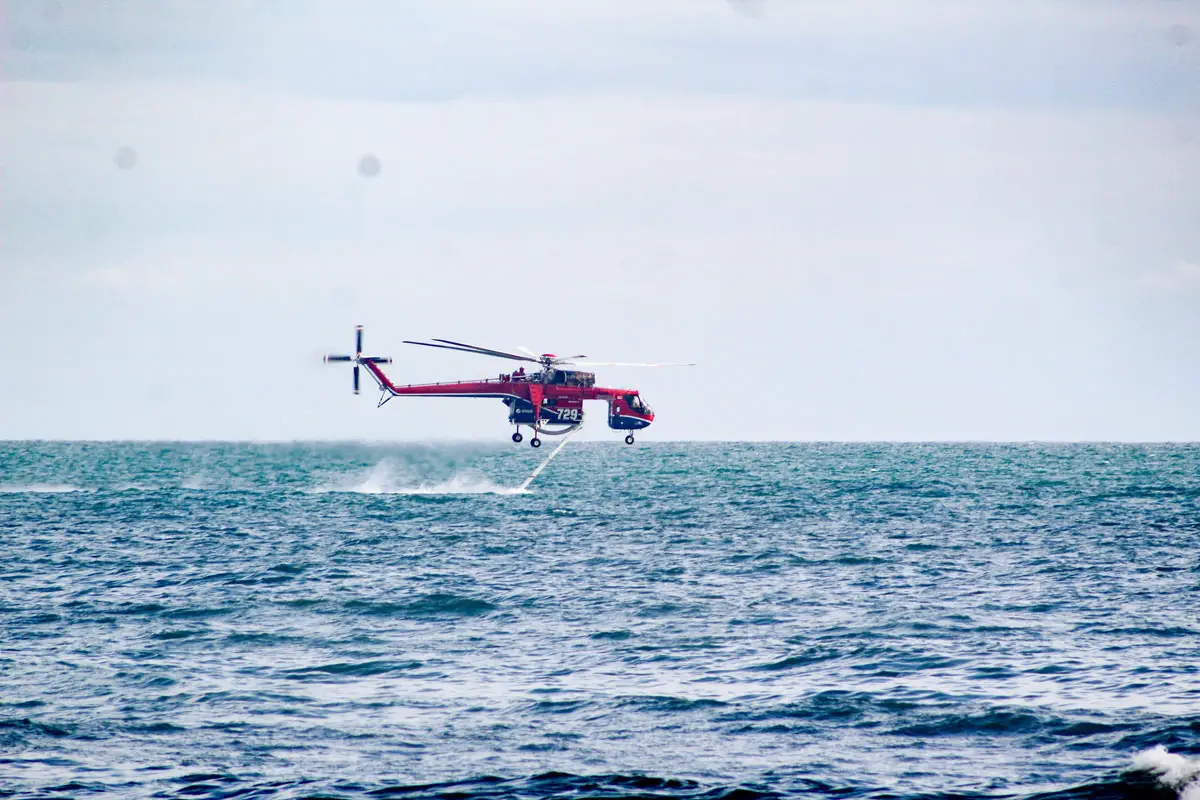 A helicopter owned by SDG&E drops ocean water onto the fire on Thursday evening at Oceanside Pier. Photo by Samantha Nelson