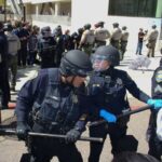 Students face riot police at UC San Diego on Monday as they attempt to block buses carrying 64 protestors arrested at the university's pro-Palestine encampment earlier that morning. Photo by Laura Place
