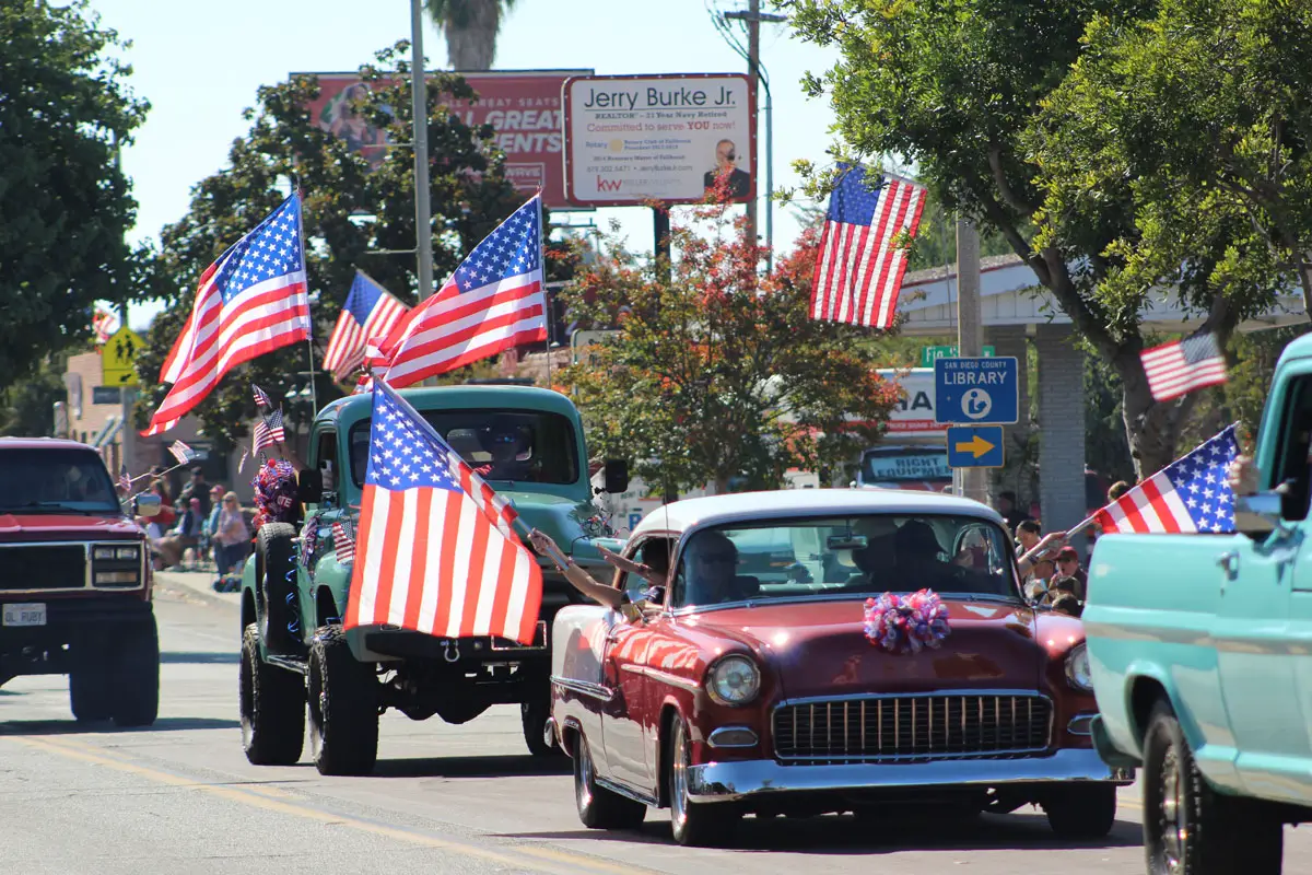 Vintage trucks and cars equipped with large American flags cruise slowly down Main Avenue as part of a Veterans Day Parade on Nov. 11 in Fallbrook. Photo by Samantha Nelson