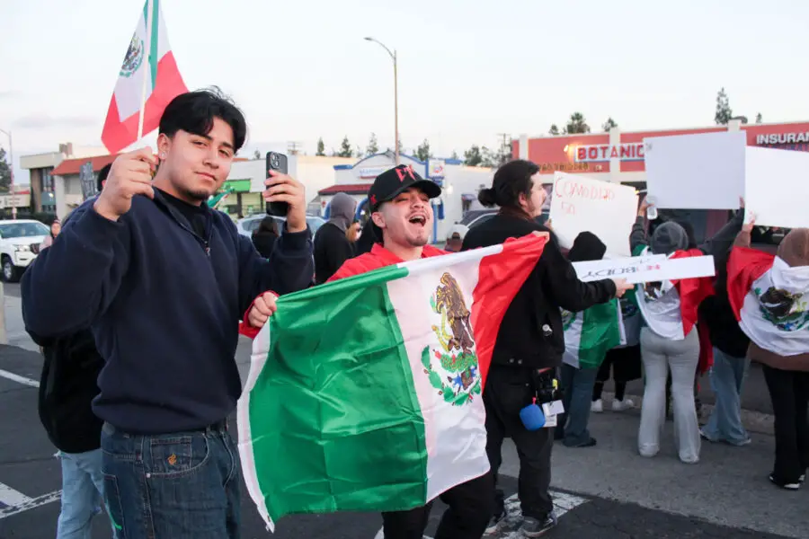 Manifestantes sostienen banderas mexicanas y carteles en respuesta al aumento de la aplicación de la ley por parte de ICE y las deportaciones, el 29 de enero en Escondido. Foto por Samantha Nelson.