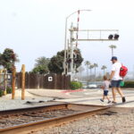 Pedestrians walk across the at-grade rail crossing at Coast Highway 101 near Seagrove Park on Tuesday. Photo by Leo Place