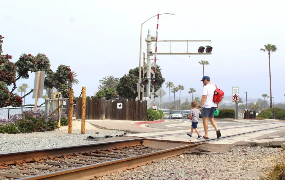 Pedestrians walk across the at-grade rail crossing at Coast Highway 101 near Seagrove Park on Tuesday. Photo by Leo Place