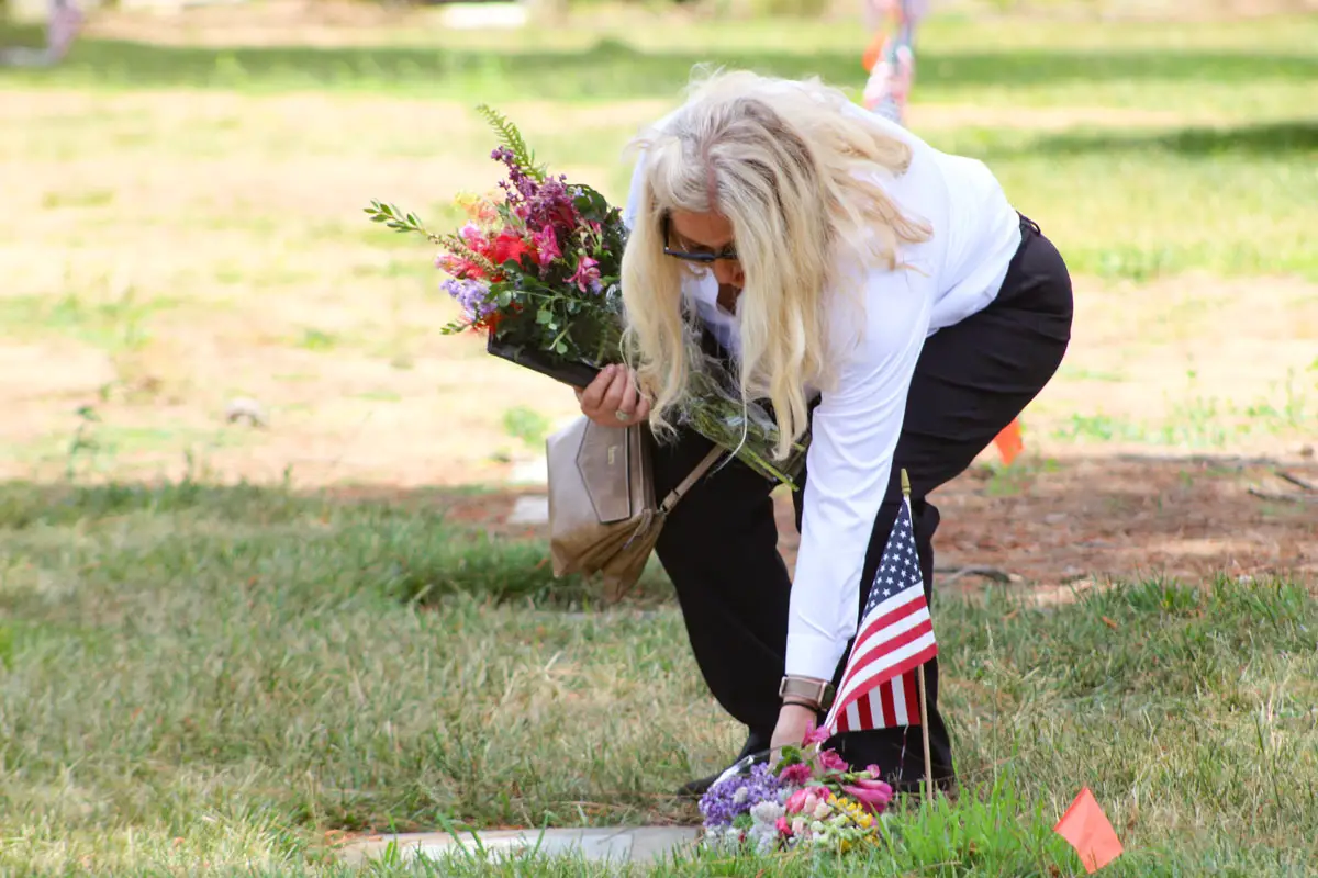 A woman places flowers at a gravesite on Memorial Day at the Fallbrook Masonic Cemetery. Photo by Samantha Nelson