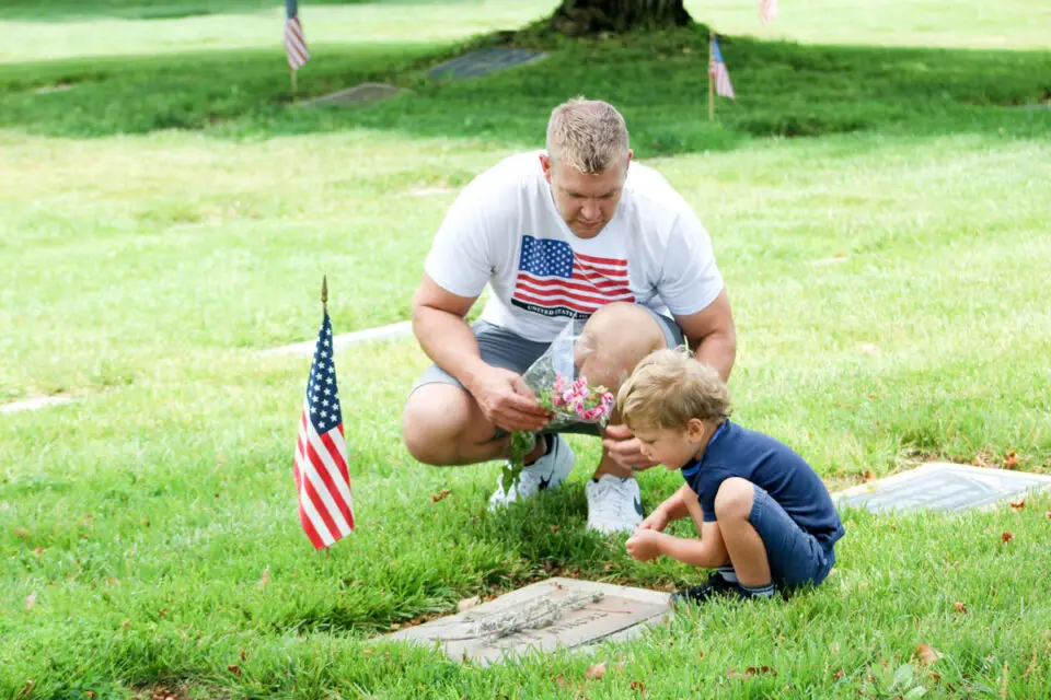 A man and child sit near a gravesite during a Memorial Day event on May 26 at Fallbrook Masonic Cemetery. Photo by Samantha Nelson