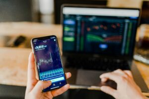 person using phone and laptop computer trading crypto-currency
