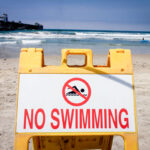A sign posted at an Oceanside beach warns visitors to stay out of the water. Photo by Frank Armstrong