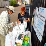 Natalie Shapiro, left, drops off food donations to the Community Resource Center in Encinitas during a food drive on Monday, alongside volunteer Duke Skaff. Photo by Leo Place