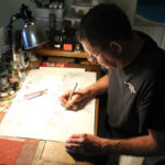 Oceanside artist Jeffrey Calkins sketches at his kitchen table studio. Photo by Jordan P. Ingram