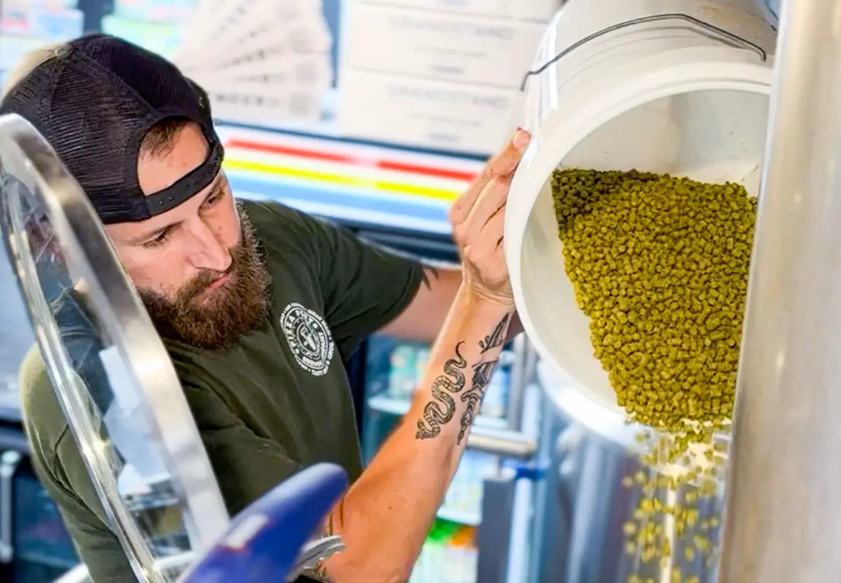 Tom Finney, head brewer at Pizza Port Imperial Beach, adds hops to a brew. Courtesy photo/Pizza Port IB