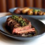 The wood-fired N.Y. strip steak, right is grilled to perfection is finished in beef tallow and served with crispy duck fat potatoes and a punchy chimichurri. Courtesy photo/CTZN