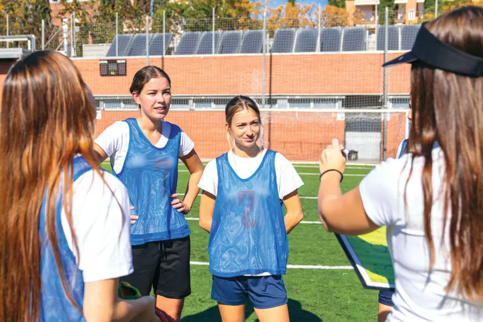 Young female athletes listen to their coach at practice.