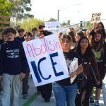 Juliet Venegas, center, and hundreds of other San Dieguito Academy students walk along Santa Fe Drive during a campus walkout on Friday to protest Immigration and Customs Enforcement. Photo by Leo Place