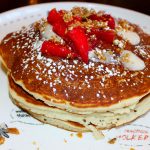 Tres Leches Pancakes-Vanilla pancakes topped with buttercream, fresh strawberries, Tres leches syrup, and pistachio brittle. Photo by Rico Cassoni