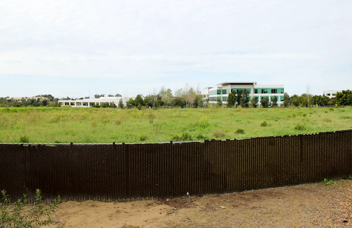 A development notice hangs on a fence surrounding a vacant industrial parcel in Bressi Ranch on Feb. 18 in Carlsbad. Toll Brothers is seeking approval to rezone the site for residential use; Viasat’s campus can be seen behind the property. Photo by Jordan P. Ingram
