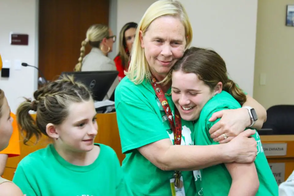 Discovery Elementary librarian Marion Peña hugs students involved in the school’s library crew after the San Marcos Unified School District voted not to cut hours and benefits for Peña and nine other school librarians on Thursday. Photo by Leo Place