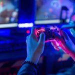 Person holding a video game controller while playing an interactive video game on a computer monitor.