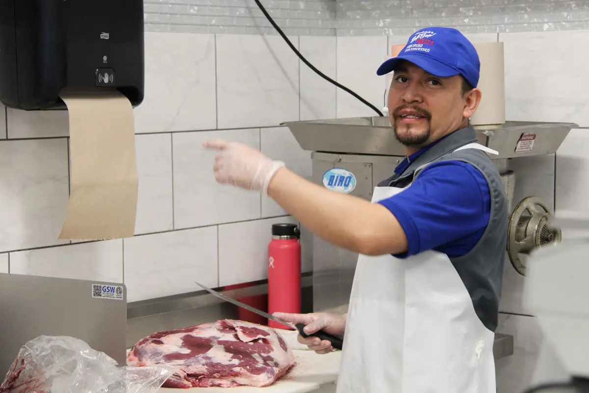 A butcher skillfully trims and prepares a large cut of beef at Tip Top Meats in Carlsbad, getting it ready for display in the shop’s case. Photo by Jordan P. Ingram