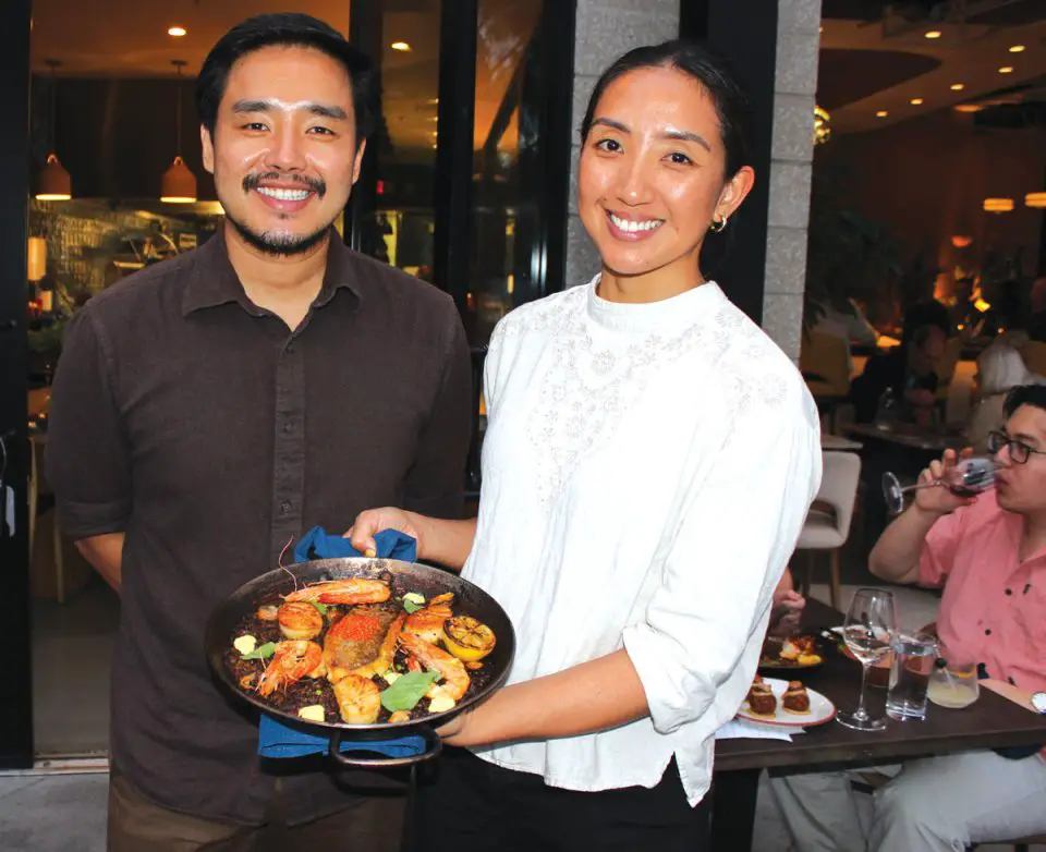 Proprietors Willy Wu Jye Hwa, left, and Karine Beers present CTZN’s signature Seafood Paella. Photo by Rico Cassoni